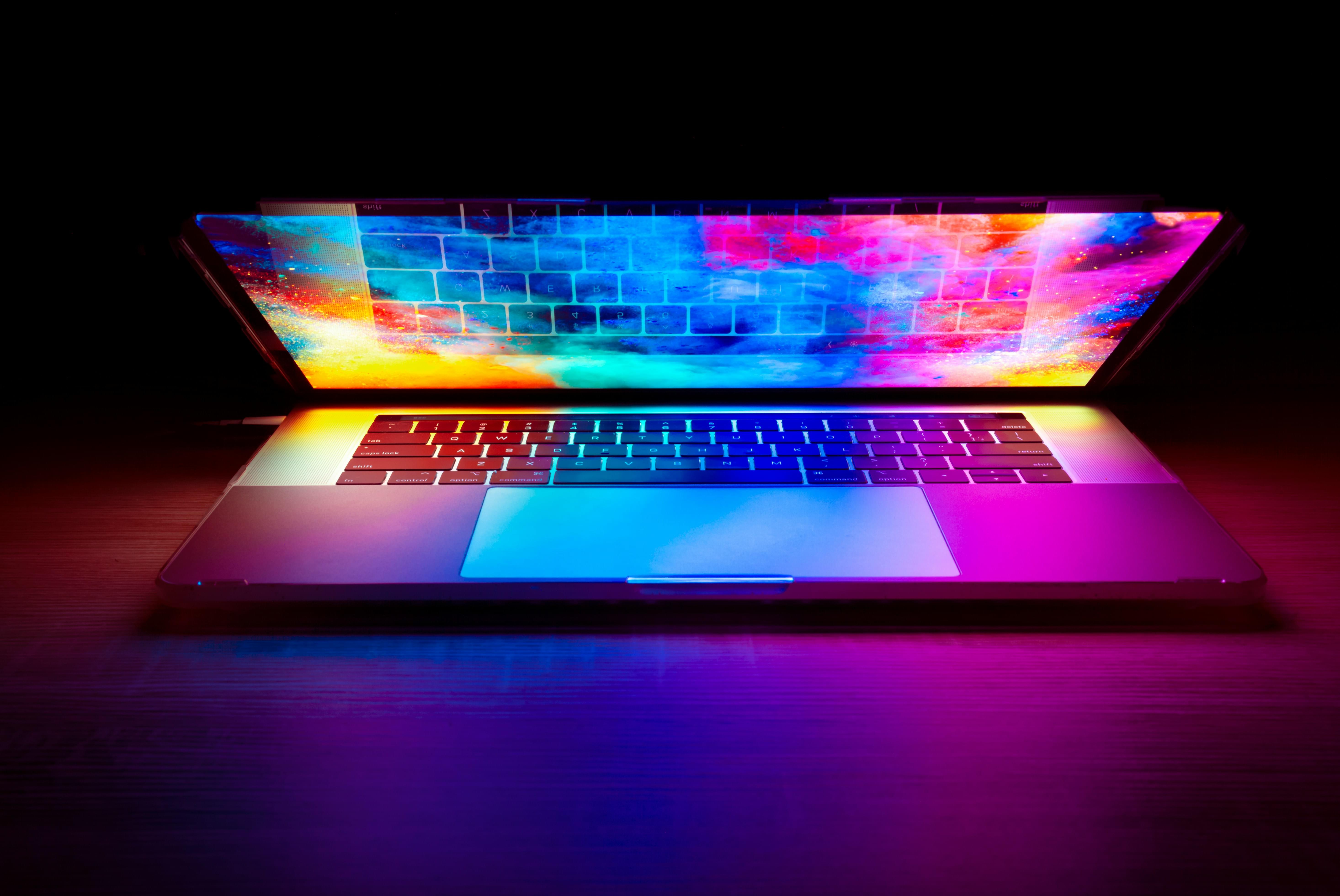 A half-closed laptop with a colorful display on a black background.